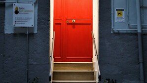 A red door with a fan above it, leading to a set of stairs. - Porta San Gennaro (Naples)
