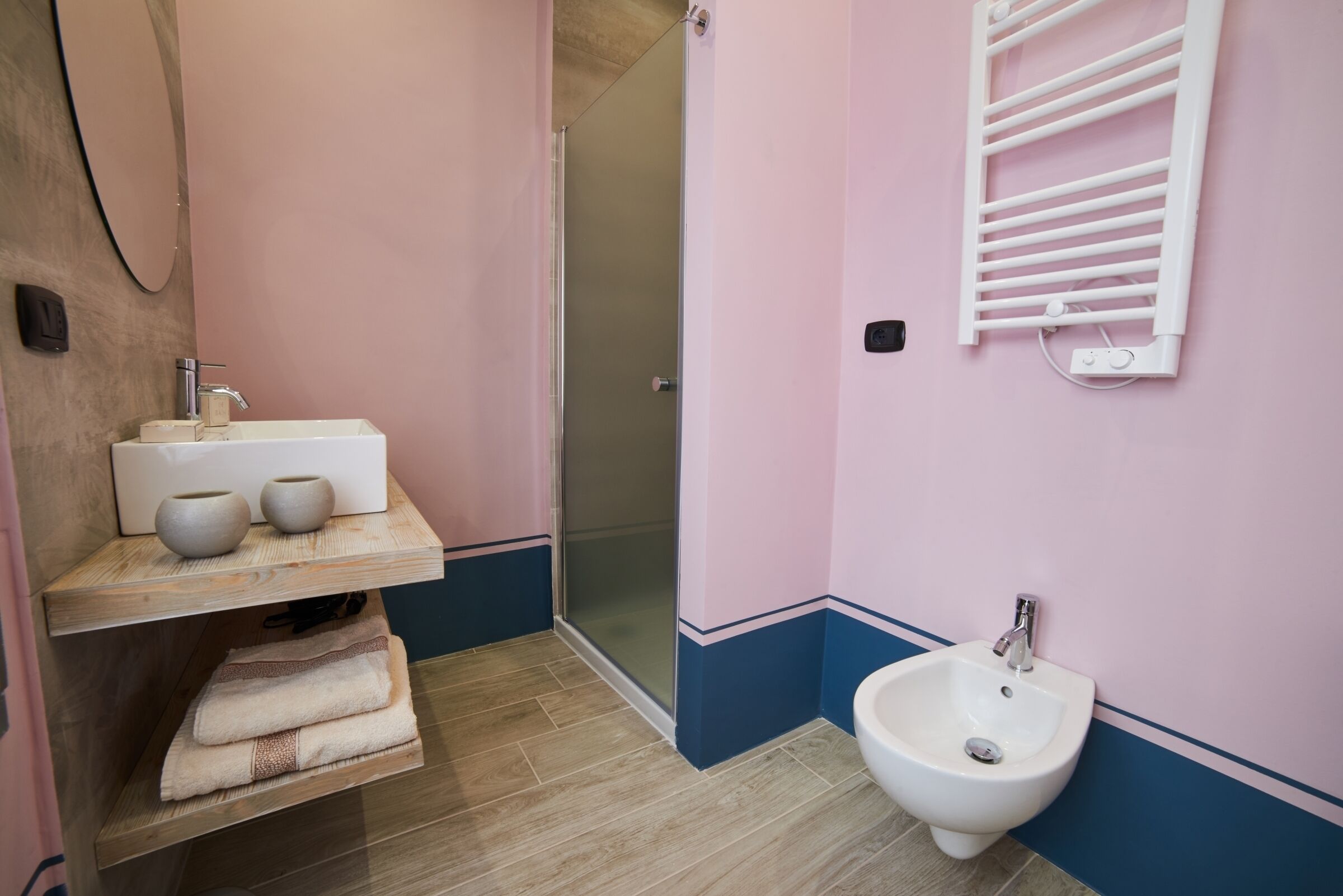 Un baño con lavamanos, bidé, toallero y cabina de ducha con mampara de vidrio.
