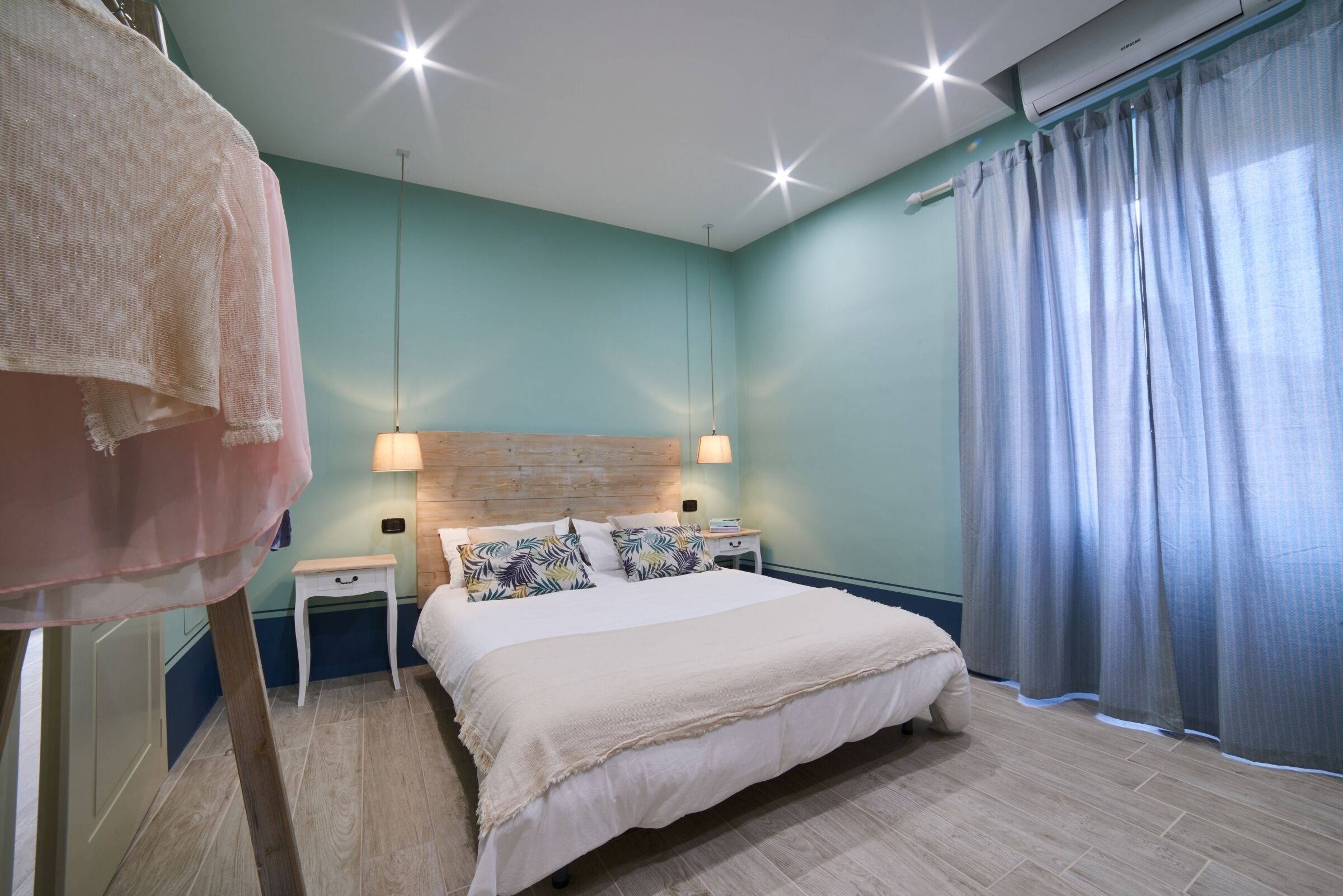 A bedroom with a bed, bedside tables, a headboard, and a window with curtains.