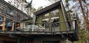 A modern cabin with a balcony, large windows, and a satellite dish.