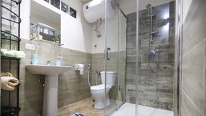 A bathroom with a glass-enclosed shower, a pedestal sink, and a toilet. - Apartment for tourist use in the center (Catania)