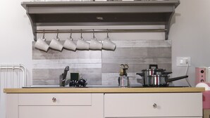 A kitchen with a wooden countertop, a built-in oven, and a microwave. There are three white plates on a shelf above the counter. - Apartment for tourist use in the center (Catania)