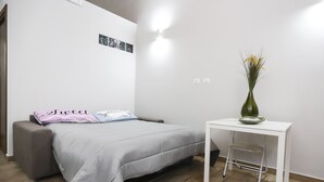 A bedroom with a bed, a small table, a chair, and a vase with flowers. - Apartment for tourist use in the center (Catania)