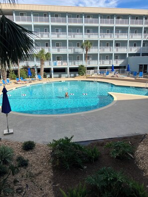 Un hôtel doté d’un espace piscine, comprenant des chaises longues et des parasols.