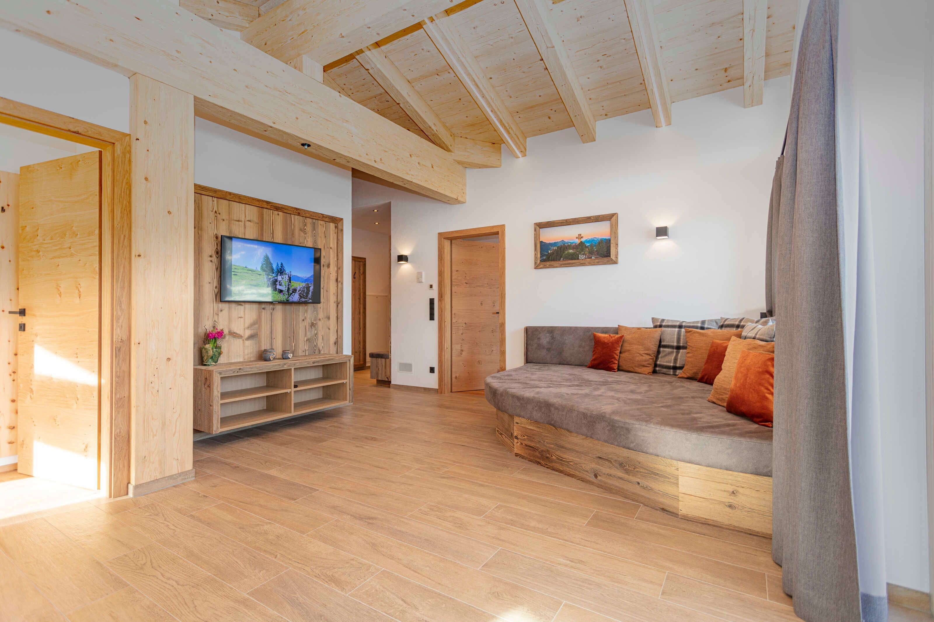 Una sala de estar moderna con piso de madera, un sofá con cojines, un televisor montado en una pared de madera y un cuadro.