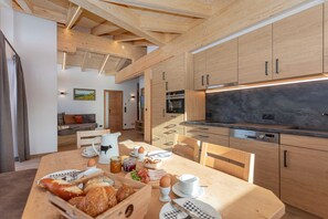 Une cuisine moderne avec des meubles en bois, un coin repas doté d’une table en bois, et une vue sur le salon.
