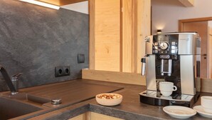 Eine moderne Küche mit integrierter Kaffeemaschine, einer Schüssel mit Nüssen und einer Kaffeetasse auf der Arbeitsfläche.
