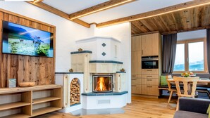 Una cocina moderna con chimenea empotrada, armarios de madera y zona de comedor con mesa y sillas.