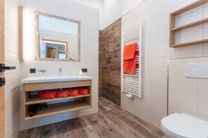 A modern bathroom with a wooden vanity, a mirror, a towel rack, and a toilet.