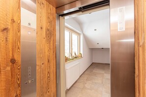 Un ascensor con paneles de madera, un radiador blanco y una ventana decorada.