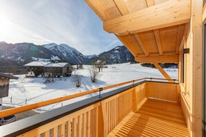 Un balcón de madera con vistas a un paisaje nevado y montañas.