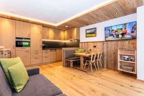 Una cocina moderna con armarios de madera, un comedor con banco y un televisor montado en la pared.