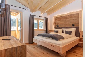 A wooden-framed bedroom with a bed, a nightstand, a table, and a window.