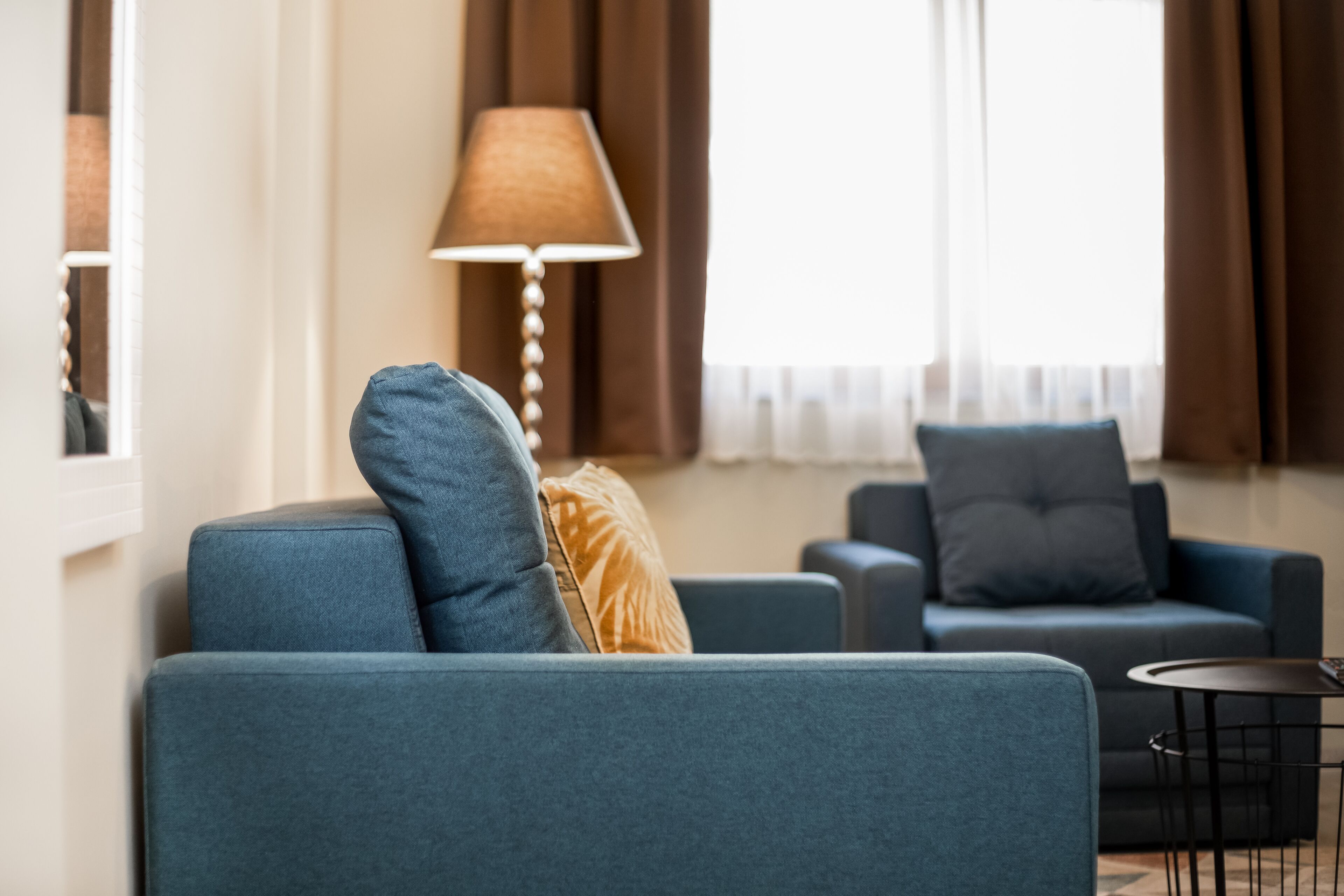 A modern living room with two blue sofas, a small round table, and a lamp.