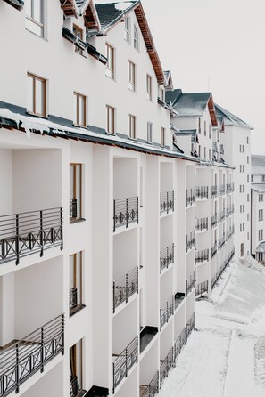 A row of white multi-story buildings with balconies and a snow-covered ground. - Sky Cabin Apartments (Raška)