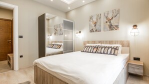 A bedroom with a large bed, a wardrobe, a nightstand, and a mirror.