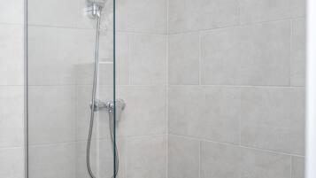 Une douche moderne avec une porte en verre, des murs carrelés et un plancher en bois.