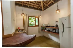 A compact kitchen with a wooden countertop, a sink, a window with curtains, and hanging pendant lights. - Eco Vila Taipu de Fora (Maraú)