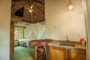 A kitchen with a rustic ceiling, a wooden bar stool, a sink, and a hanging light fixture. - Eco Vila Taipu de Fora (Maraú)