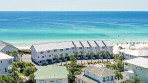 A beachfront hotel with multiple-story buildings, a sandy beach, and clear blue waters. - Walton Dunes 7,  Beachfront, Private Beach.  2 Chair/1 Umbrella Set up Included. (Santa Rosa Beach)