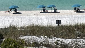 A beach with clear turquoise water, several beach chairs, and blue umbrellas. - Walton Dunes 7,  Beachfront, Private Beach.  2 Chair/1 Umbrella Set up Included. (Santa Rosa Beach)