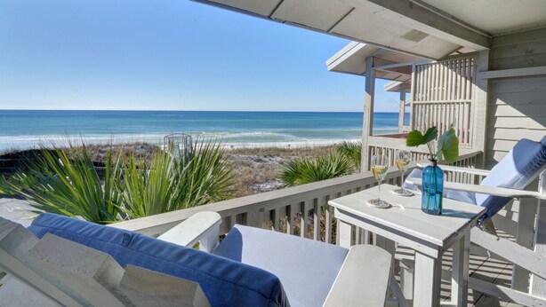 A balcony with a view of the beach, a table with a vase, and two chairs. - Walton Dunes 7,  Beachfront, Private Beach.  2 Chair/1 Umbrella Set up Included. (Santa Rosa Beach)