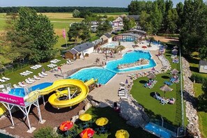 Un complexe hôtelier doté de plusieurs piscines, d’un toboggan aquatique et de chaises longues.