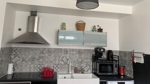 Una cocina moderna con una campana de acero inoxidable, un lavamanos doble, un microondas y una cafetera.