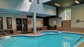 Una piscina interna con acqua cristallina, ringhiere di sicurezza e un salvagente.