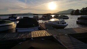 Un molo con diverse imbarcazioni ormeggiate, un pontile di legno e un tramonto sullo sfondo.