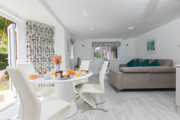 A modern dining area with a round table, white chairs, and a beige sofa.