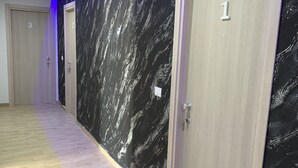 A hallway with a marble-patterned wall, wooden doors numbered 1 and 3, and a herringbone-patterned floor. - The Lux (Adrano)