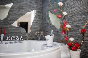 Ein modernes Badezimmer mit einer großen Badewanne, einem Spiegel und Zierblumen.