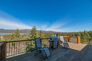 Una terrazza con barbecue, due sedie e vista su un lago e montagne.