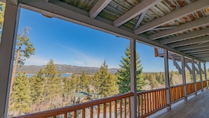 A covered outdoor area with a wooden railing, a view of a lake, and surrounding trees. - Valley View Cabin,Lake view, 6 bedrooms, Hot tub, walk distance to village (Big Bear Lake)