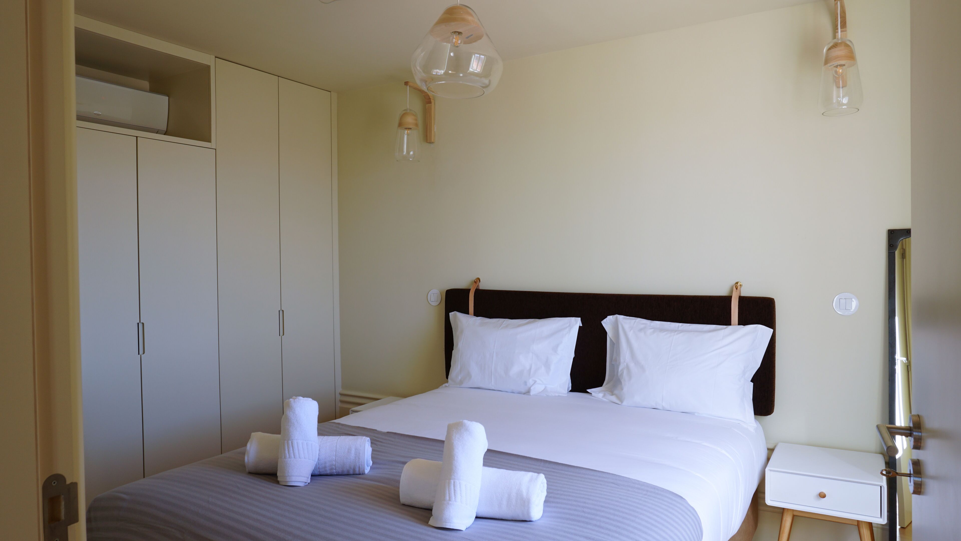 A hotel room with a bed, two bedside tables, a wardrobe, and a mirror.
