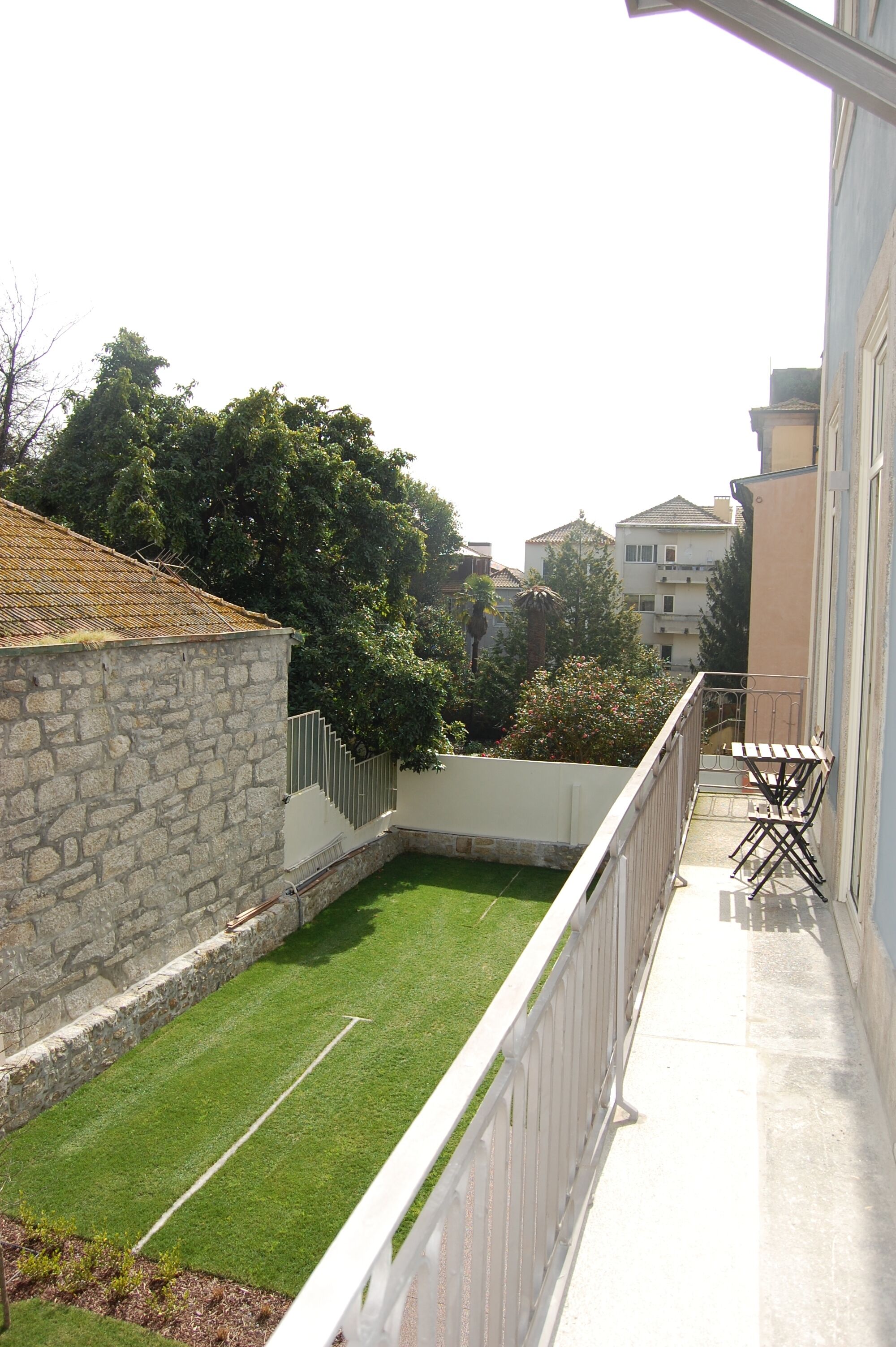 A balcony with a white railing, a small table, and a chair.