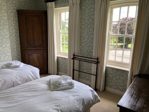 Habitación de hotel con dos camas, un armario de madera y una ventana con cortinas.
