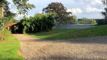 A gravel path leading to a grassy area with trees and a brick structure.
