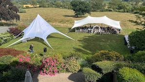 Una grande tenda bianca montata in un prato, con vista su un paesaggio lontano.