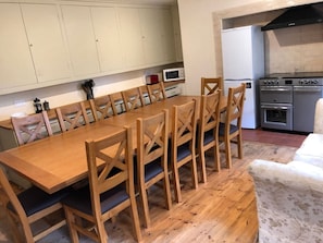 Un comedor con mesa y sillas de madera, un microondas y una estufa al fondo.