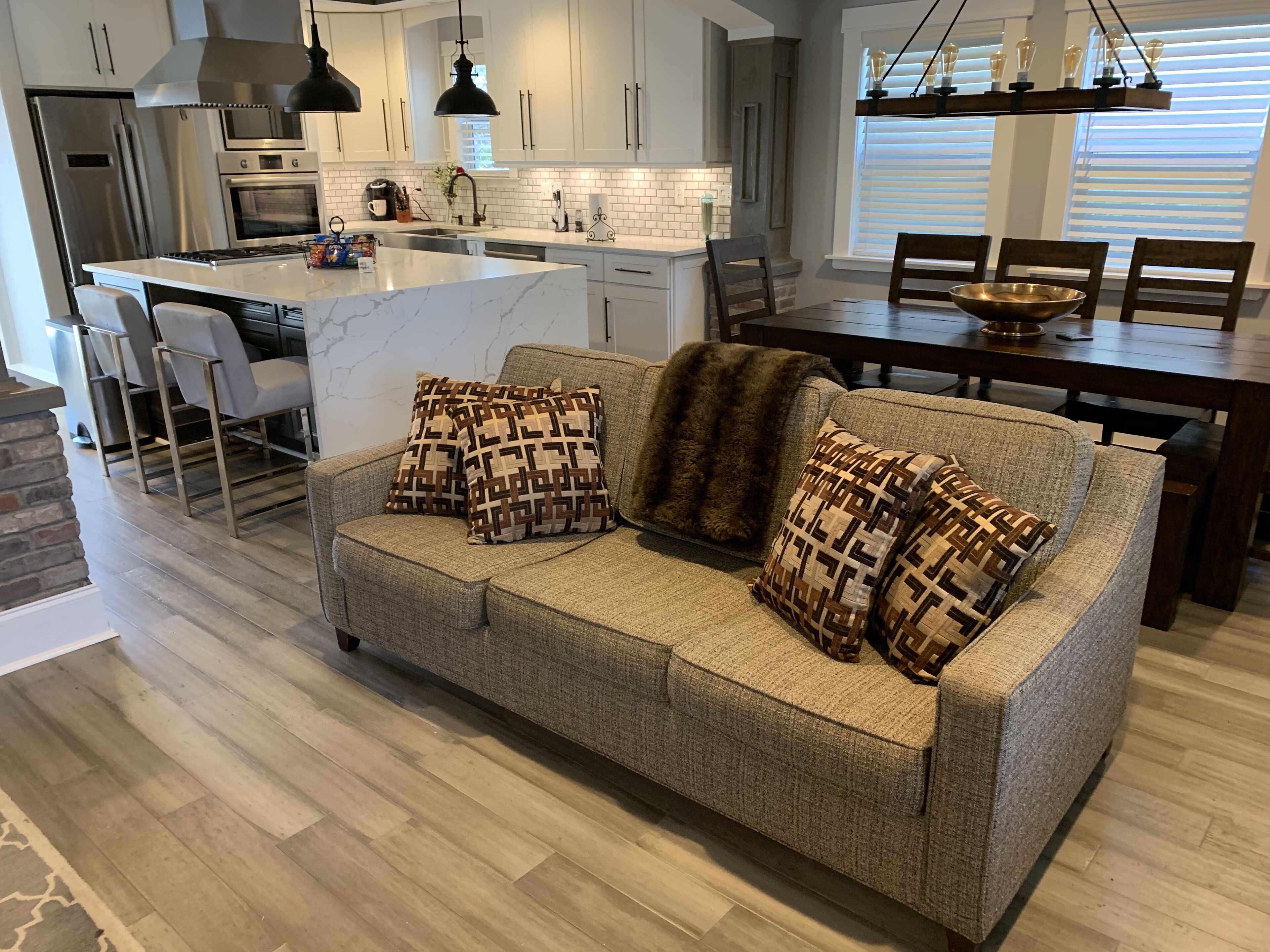 A modern kitchen with white cabinets, a central island, and a dining area with a wooden table and chairs.