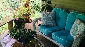 A covered porch with a wicker sofa, potted plants, and a small table. - Luxury listing close to stadium and downtown (State College)