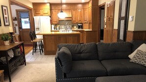 A modern kitchen with wooden cabinets, a central island, and a dining area with chairs. - Luxury listing close to stadium and downtown (State College)