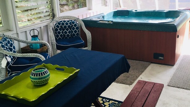 A room with a hot tub, a table with a blue tablecloth, wicker chairs, and a bench. - Luxury listing close to stadium and downtown (State College)