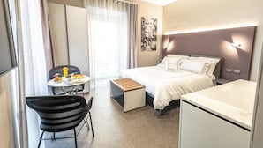 A modern hotel room with a bed, bedside table, chair, and a small desk area. - il Divino (Naples)