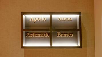 Una targa appesa al muro con i nomi Apollo, Atena, Artemide ed Ermes.