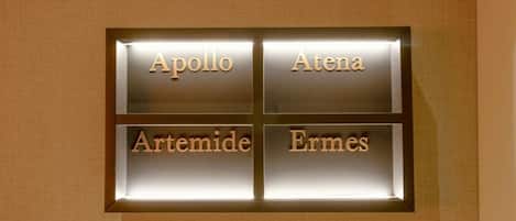 A wall-mounted sign with four names: Apollo, Athena, Artemis, and Ermes.