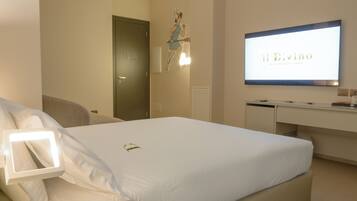 A hotel room with a bed, a desk, and a TV displaying 'il Divino Bed & Breakfast Napoli'.