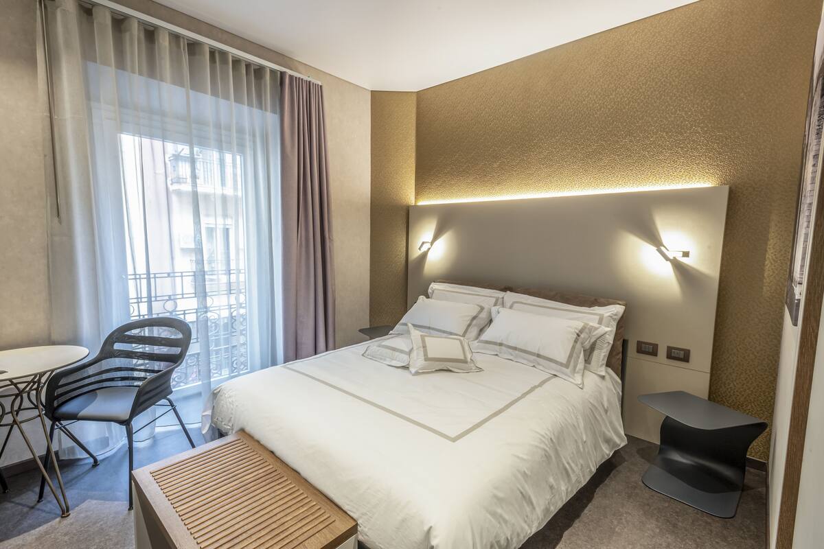 Habitación de hotel con cama, escritorio, silla y una mesita.